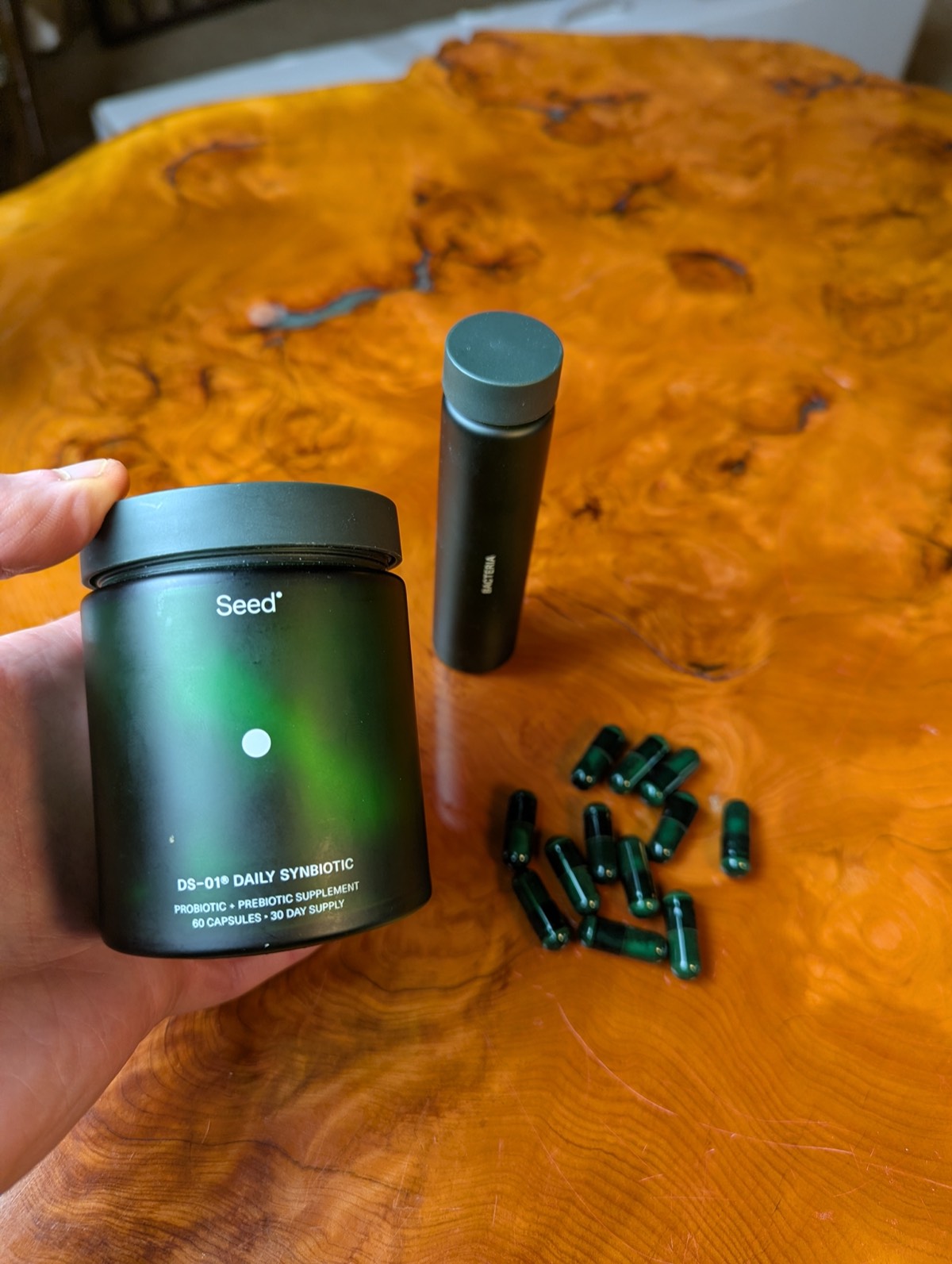 daryl holding the seed probiotic with jar and open capsules on the table