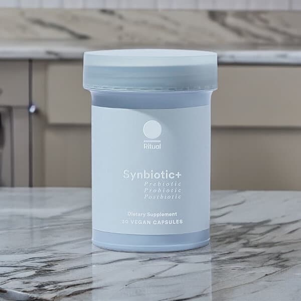 A person holding a single Ritual Synbiotic+ capsule, a key part of the daily gut health routine reviewed here.
